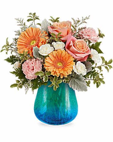 Ocean Sunrise Bouquet - As radiant as a seaside sunrise, the Ocean Sunrise Bouquet brings together coral roses, peach gerberas, and pink blooms in a turquoise glass vase with a stunning crackled gradient finish. A cheerful and uplifting gift for any occasion. Ocean Sunrise Bouquet features coral roses, pink carnations, white miniature carnations, peach gerberas, white limonium, dusty miller, leatherleaf fern, and pitta negra, arranged in a Blue Hues Vase, a translucent glass vase with a turquoise gradient and crackled design. Approximately 13 1/2" W x 13 1/4" H