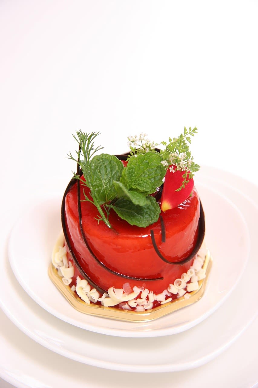 Small red glazed cake topped with fresh herb sprigs on a white plate