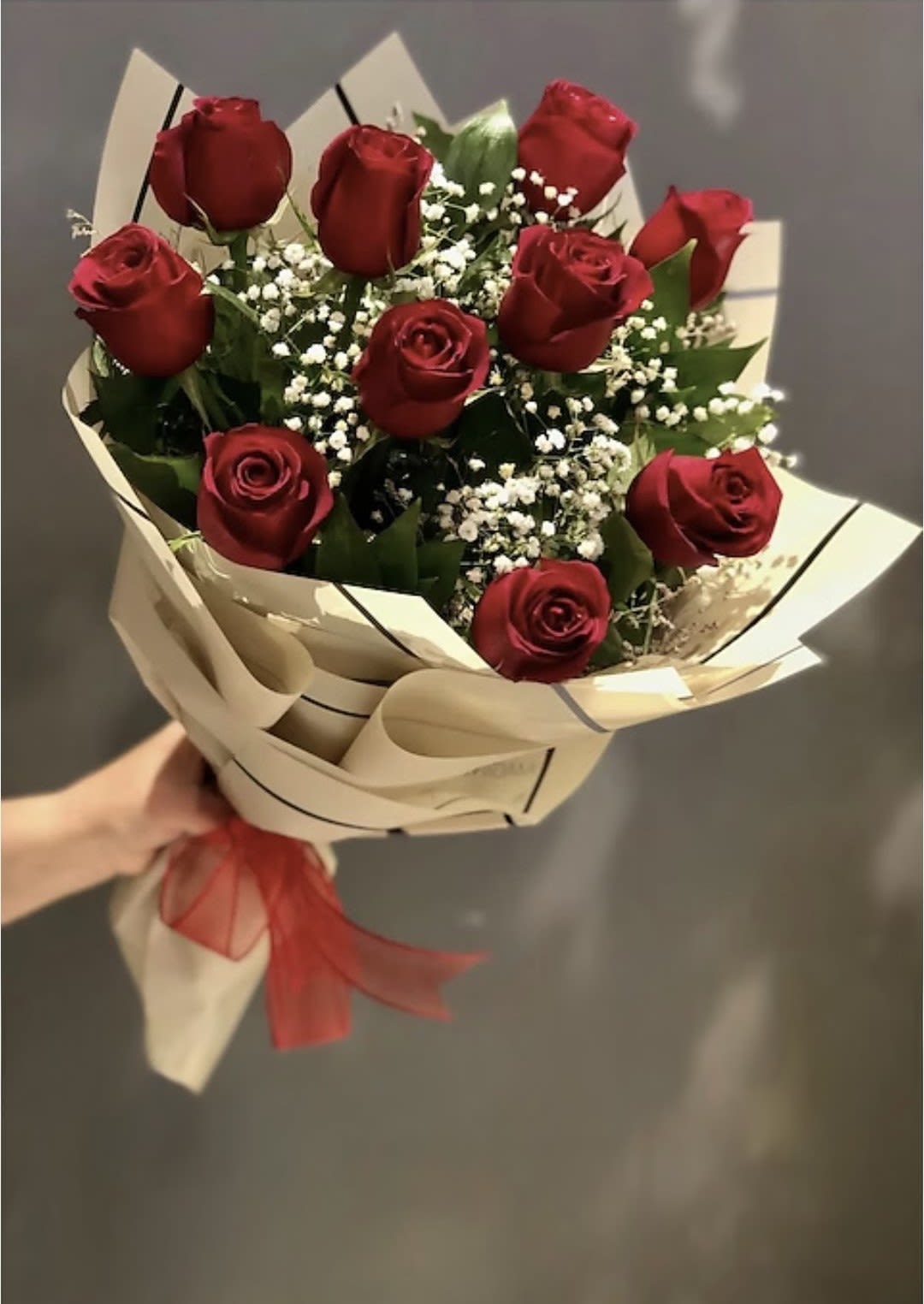 Bouquet of red roses with baby's breath in cream wrapping