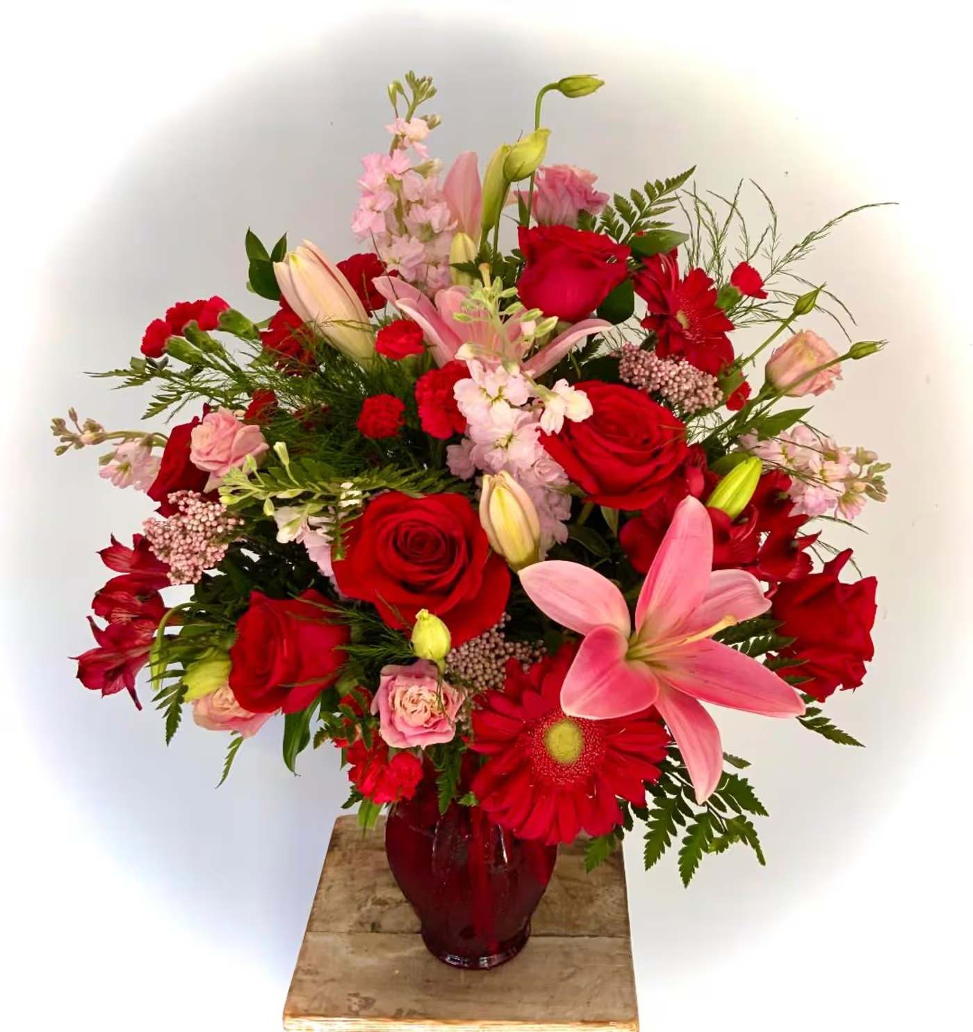 Red and pink mixed bouquet in a red glass vase