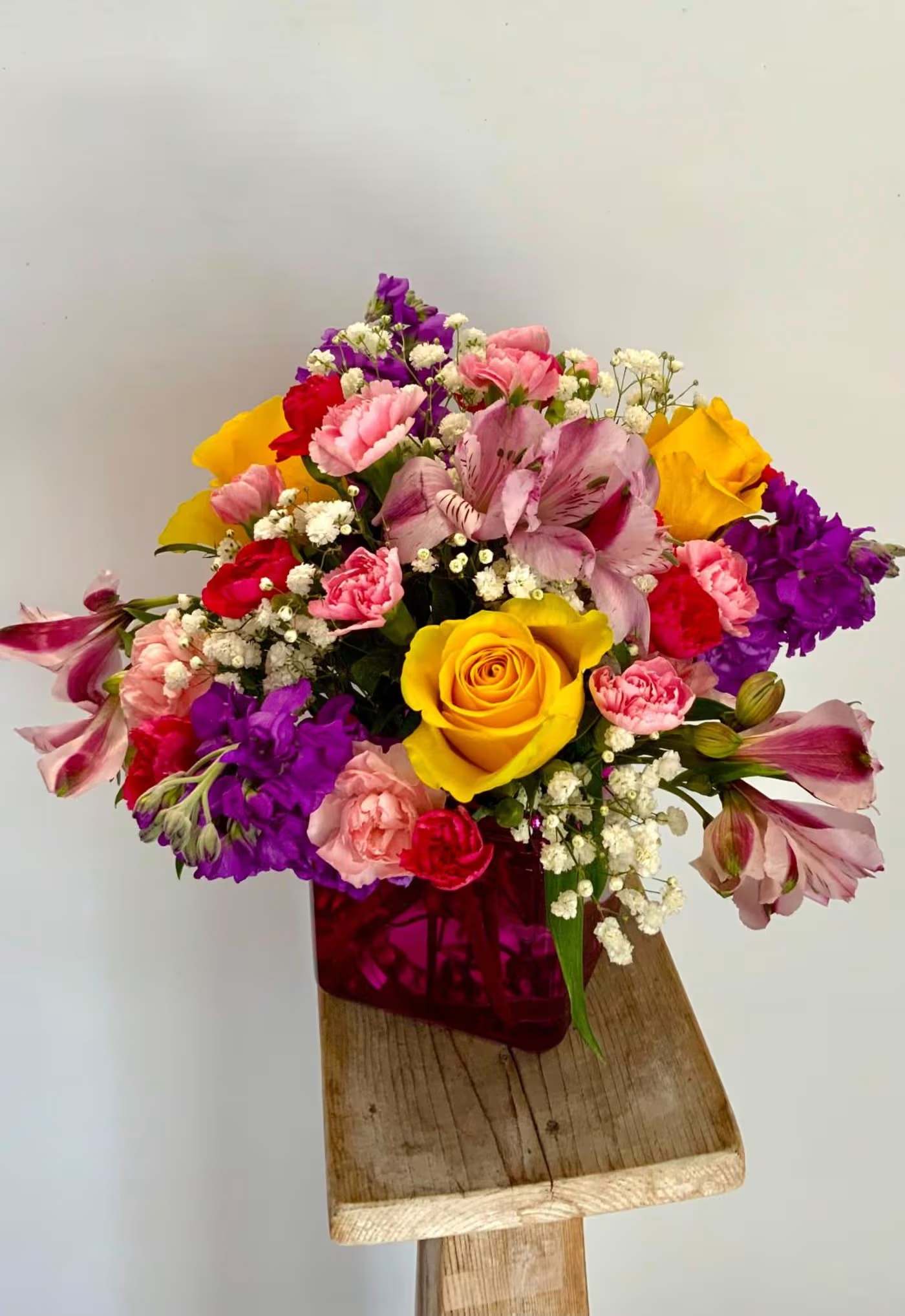Mixed bouquet with yellow roses, pink and purple flowers in a magenta vase