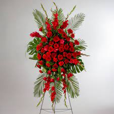 Tall standing spray of red flowers with palm fronds on a metal easel