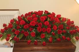 Large casket spray of red roses on a wooden casket