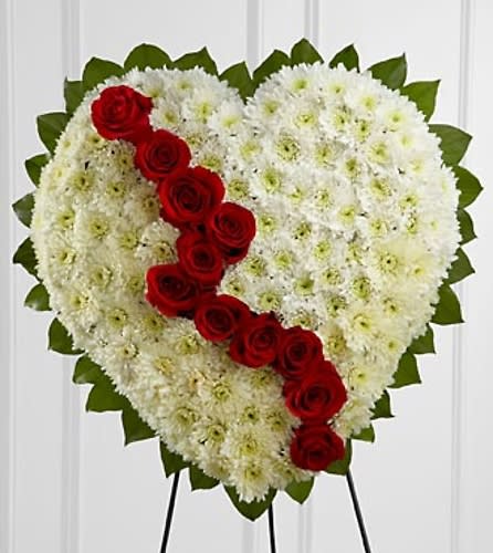 Heart-shaped white floral tribute with a diagonal line of red roses
