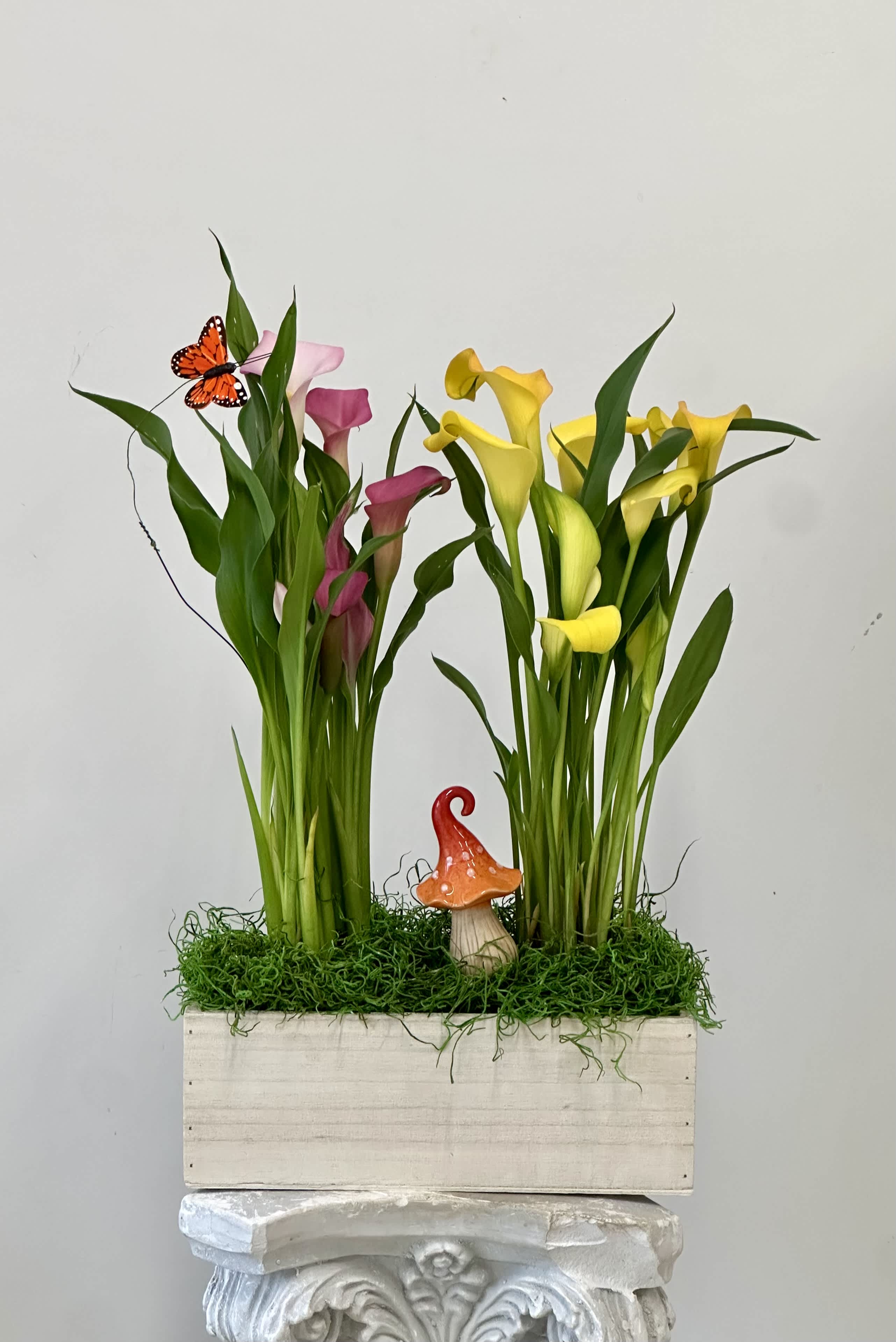 Two calla lily arrangements in a wooden box with a small mushroom accent