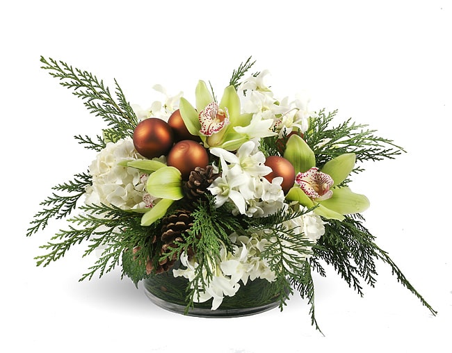 White flowers and green orchids in a low glass bowl with pinecones and copper ornaments