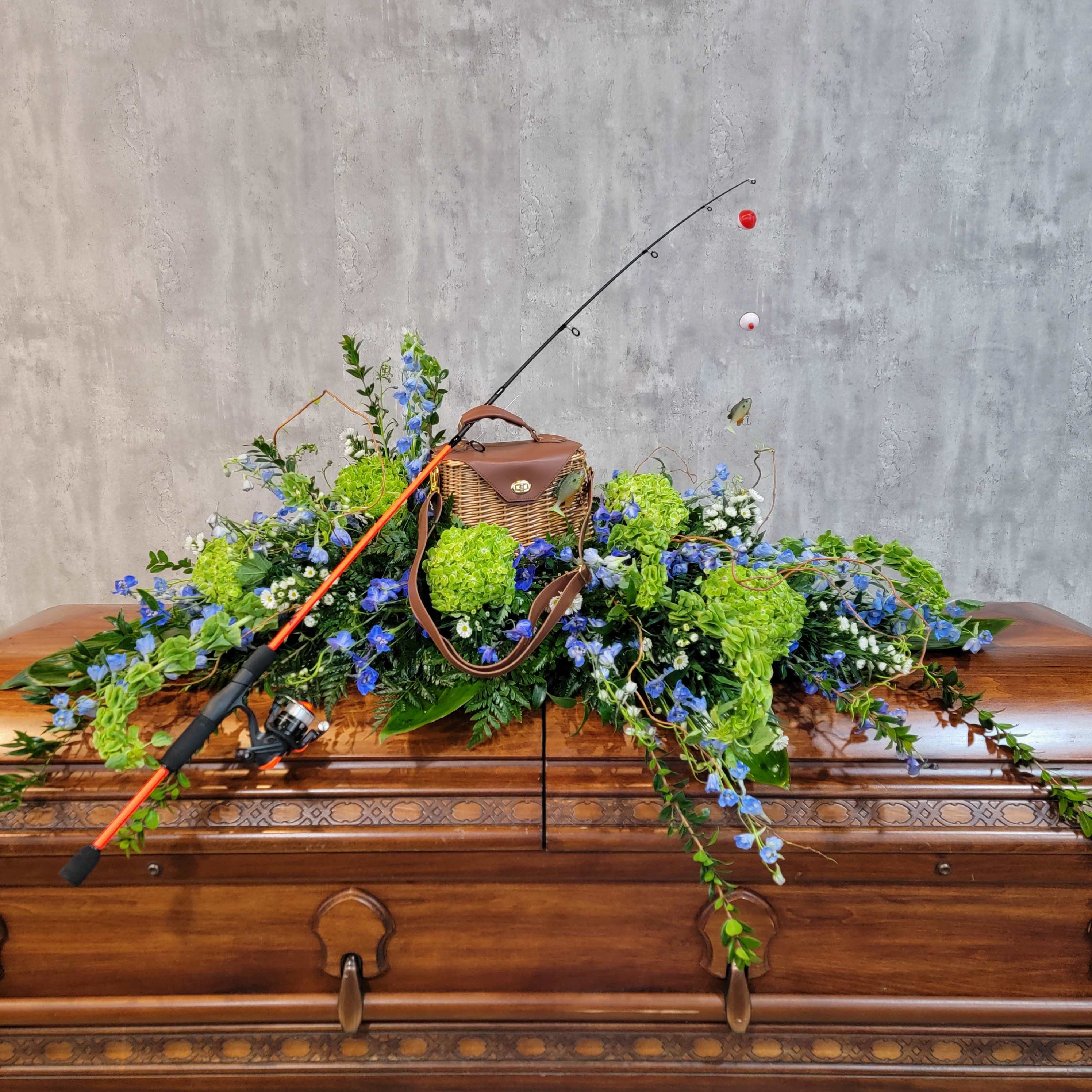Fishing rod resting on a casket with blue and green floral spray