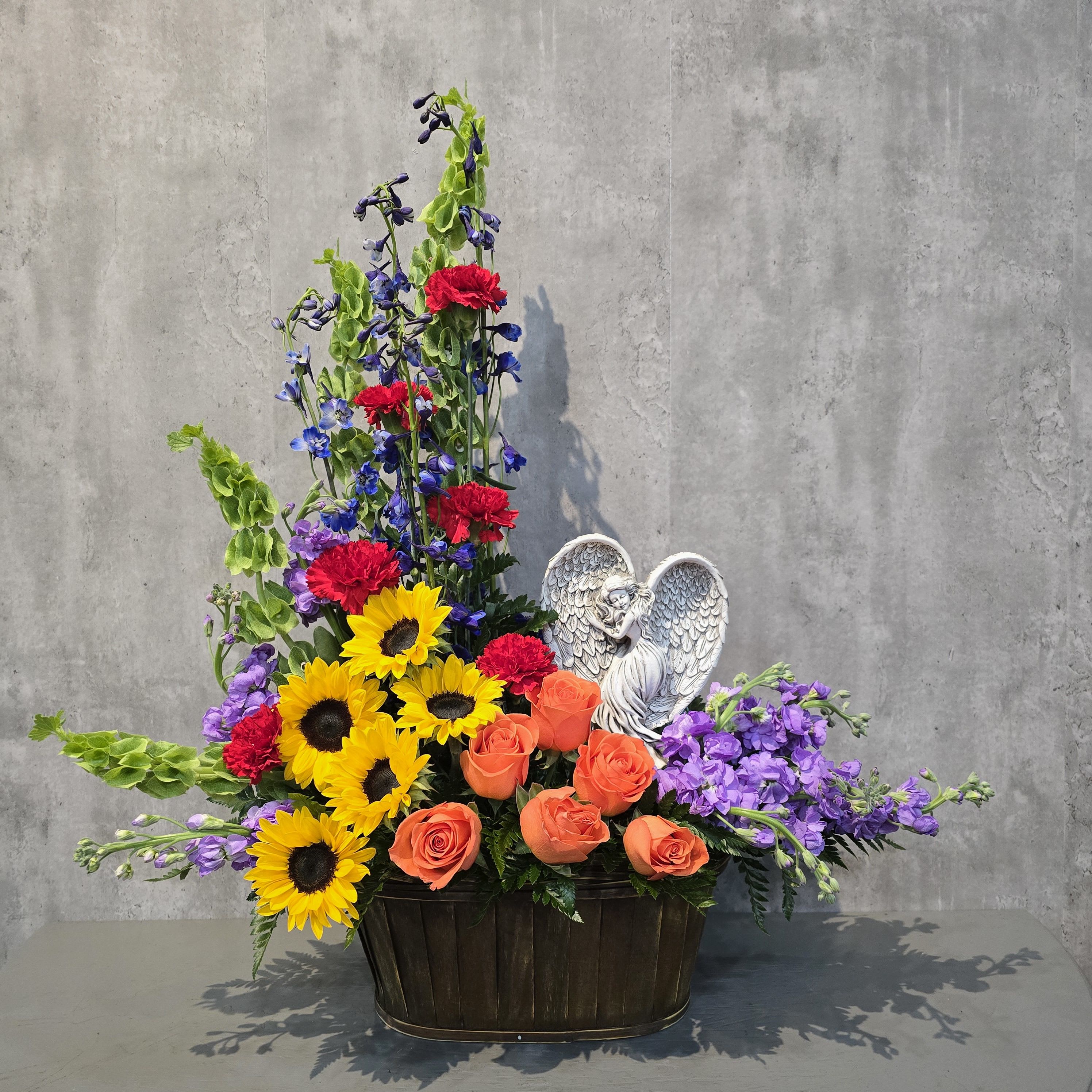 Mixed bouquet in a dark basket with sunflowers, roses, and purple blooms