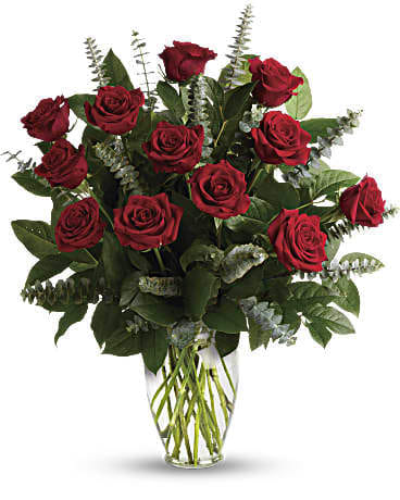 Tall arrangement of long-stemmed red roses in a clear glass vase