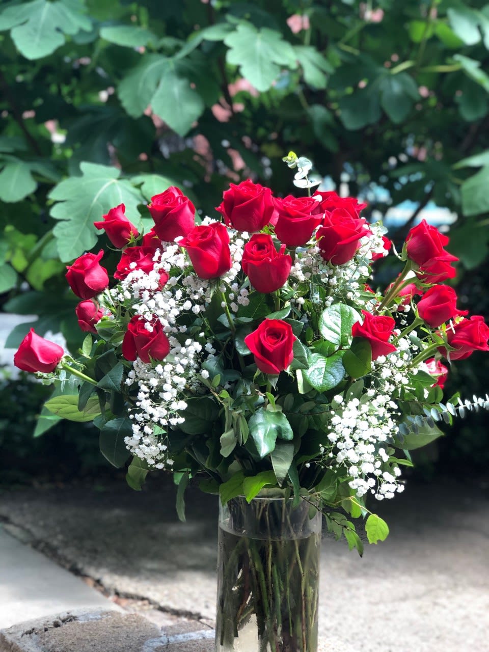 Bouquet of red roses and white baby's breath in a glass vase