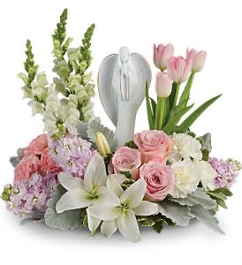 Pastel sympathy arrangement with white lilies, pink roses and tulips around an angel figurine