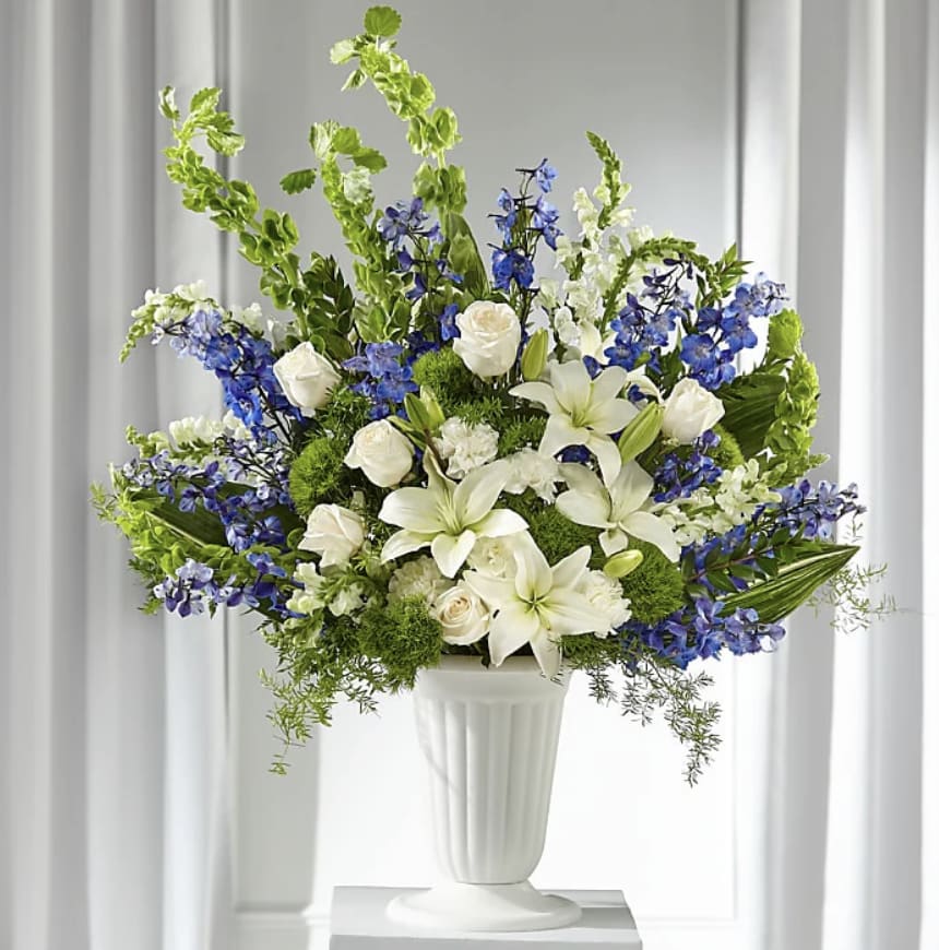 White lilies and roses with blue flowers in a white vase