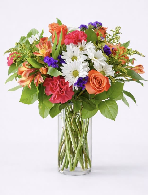 Mixed bouquet of orange, pink, and white flowers in a clear glass vase