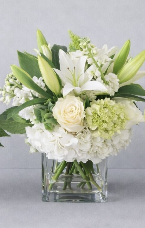 White lilies and roses arranged in a clear glass vase