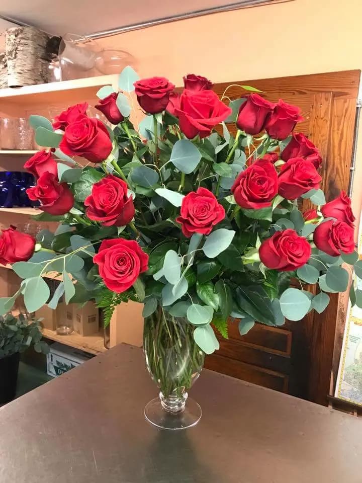 Bouquet of red roses in a clear glass vase with eucalyptus