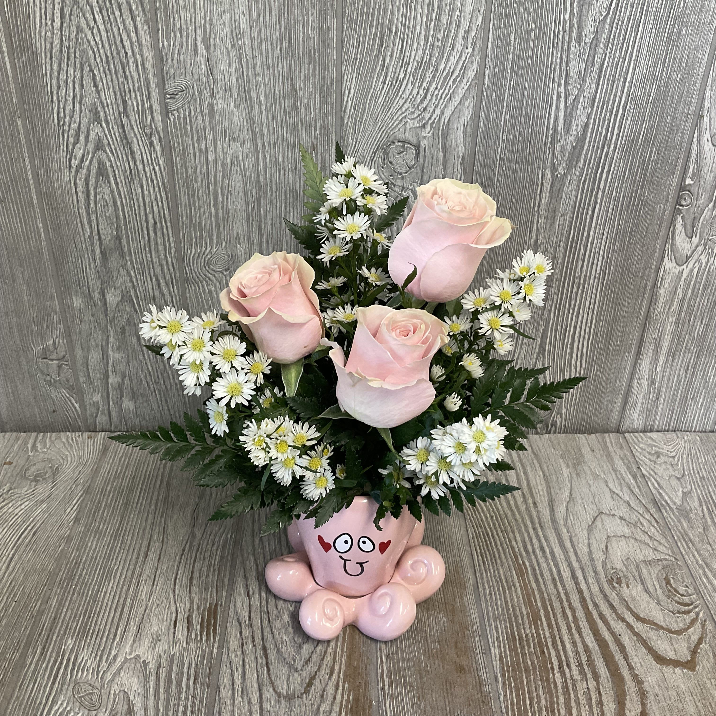 Pink roses and white daisies arranged in a pink cartoon vase