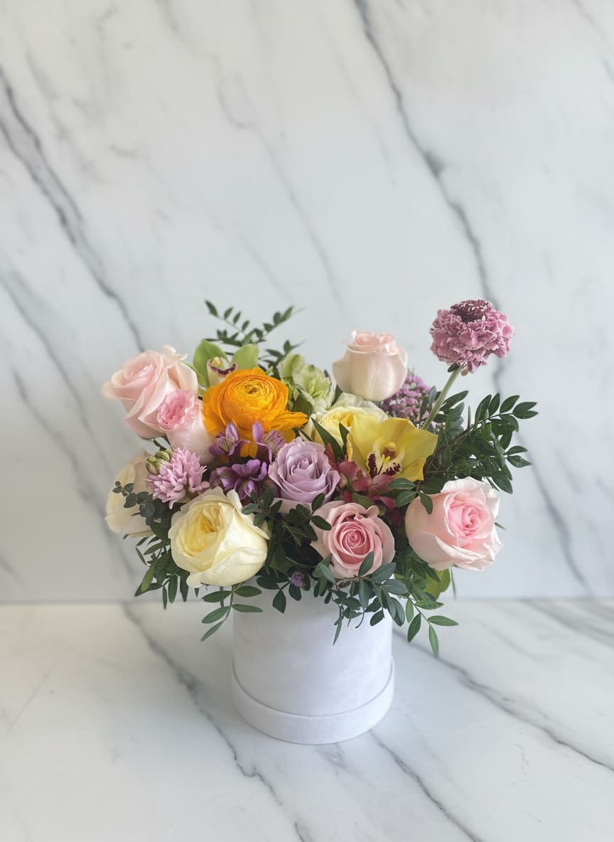 Mixed pastel flower arrangement in a white hat box