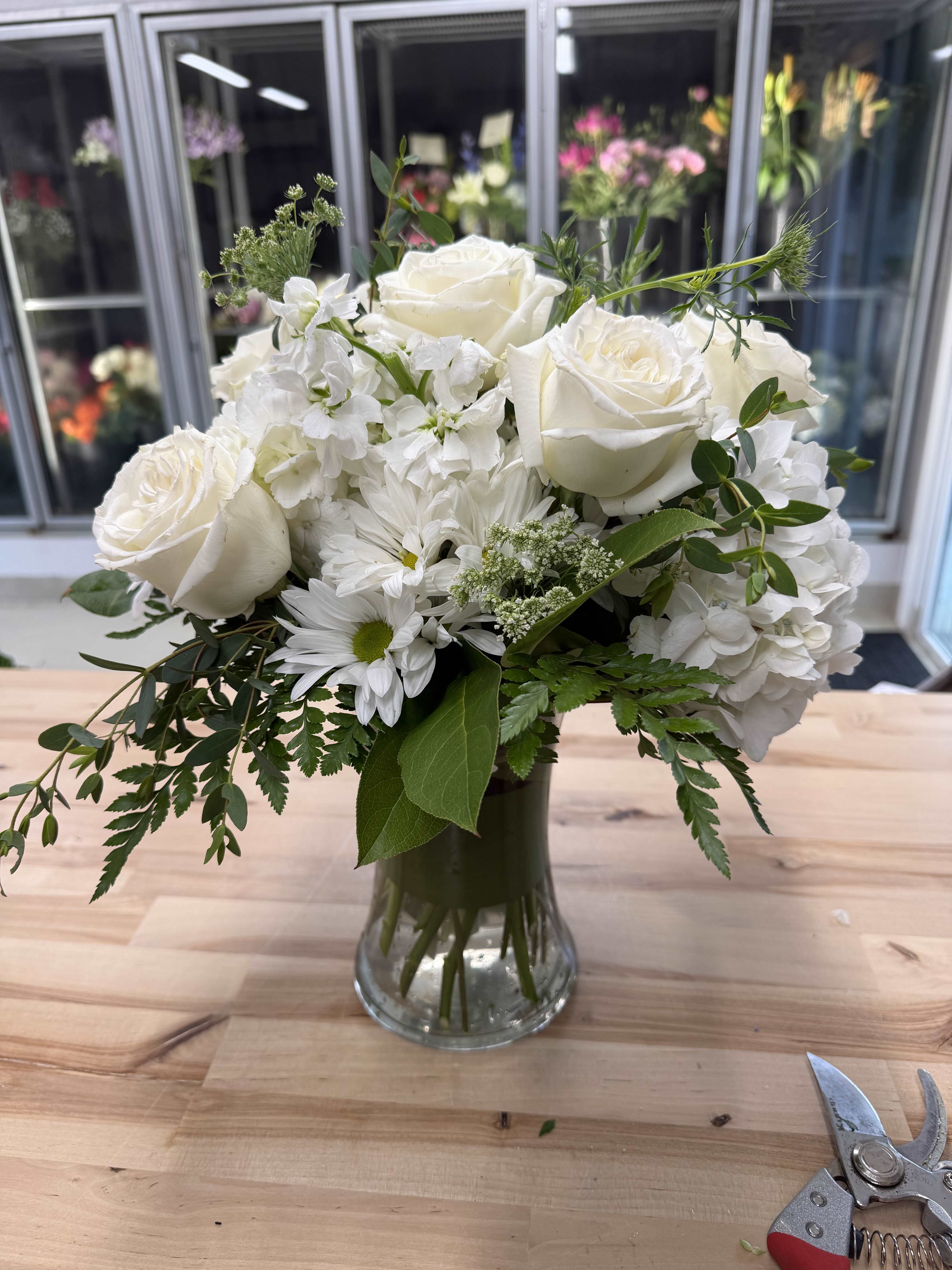 White rose and daisy bouquet in a clear glass vase