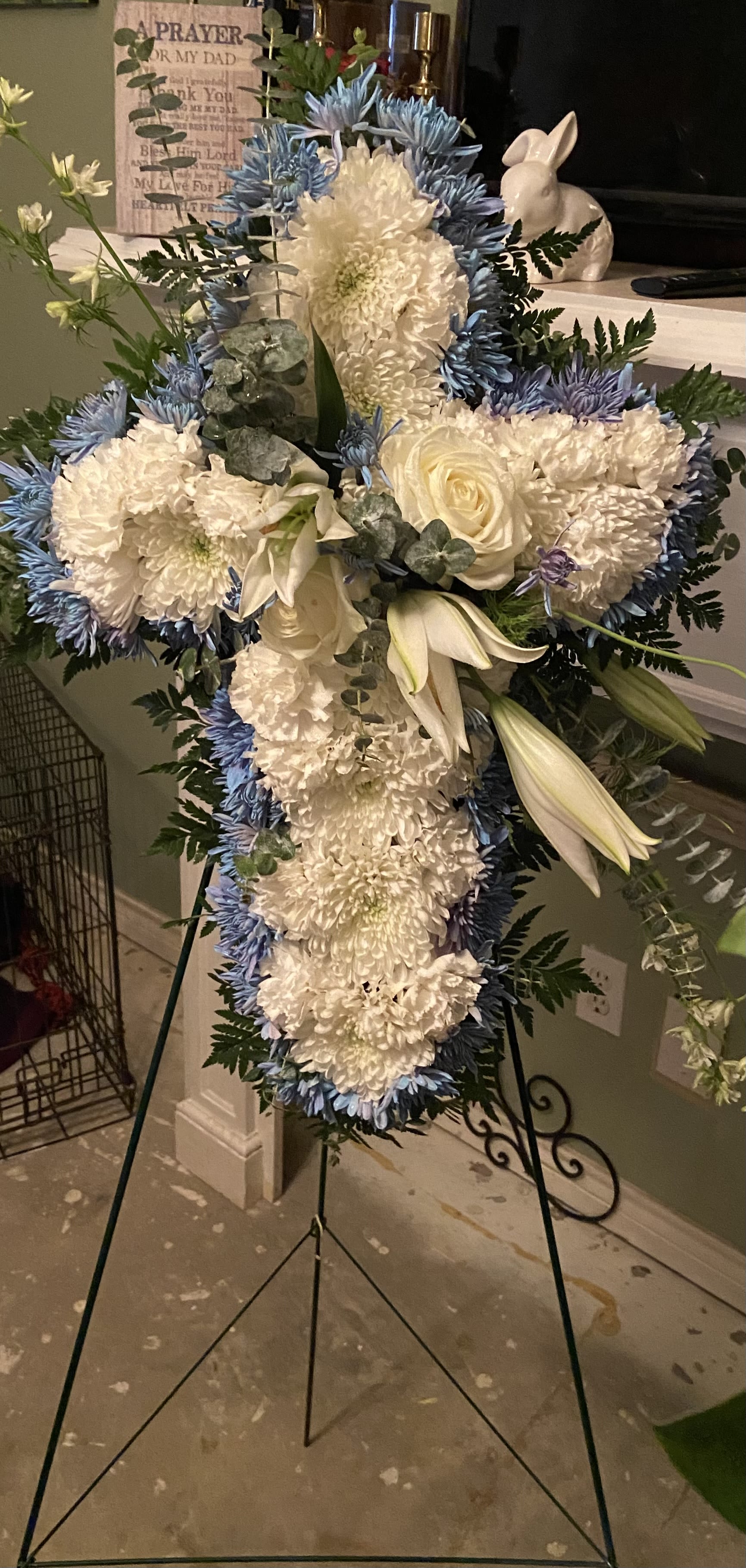 Standing floral cross with white and blue flowers on an easel