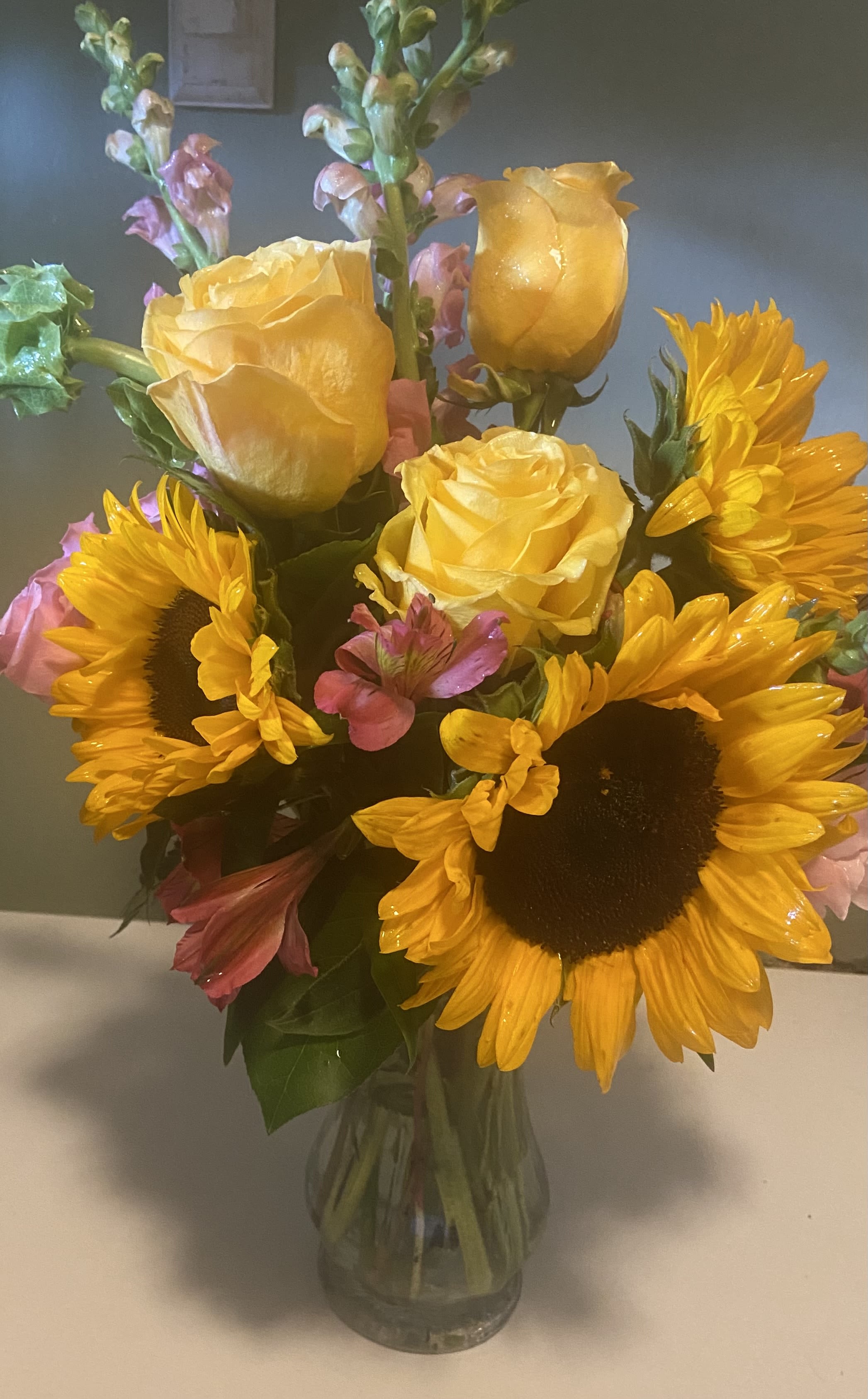 Bouquet of yellow roses and sunflowers in a glass vase