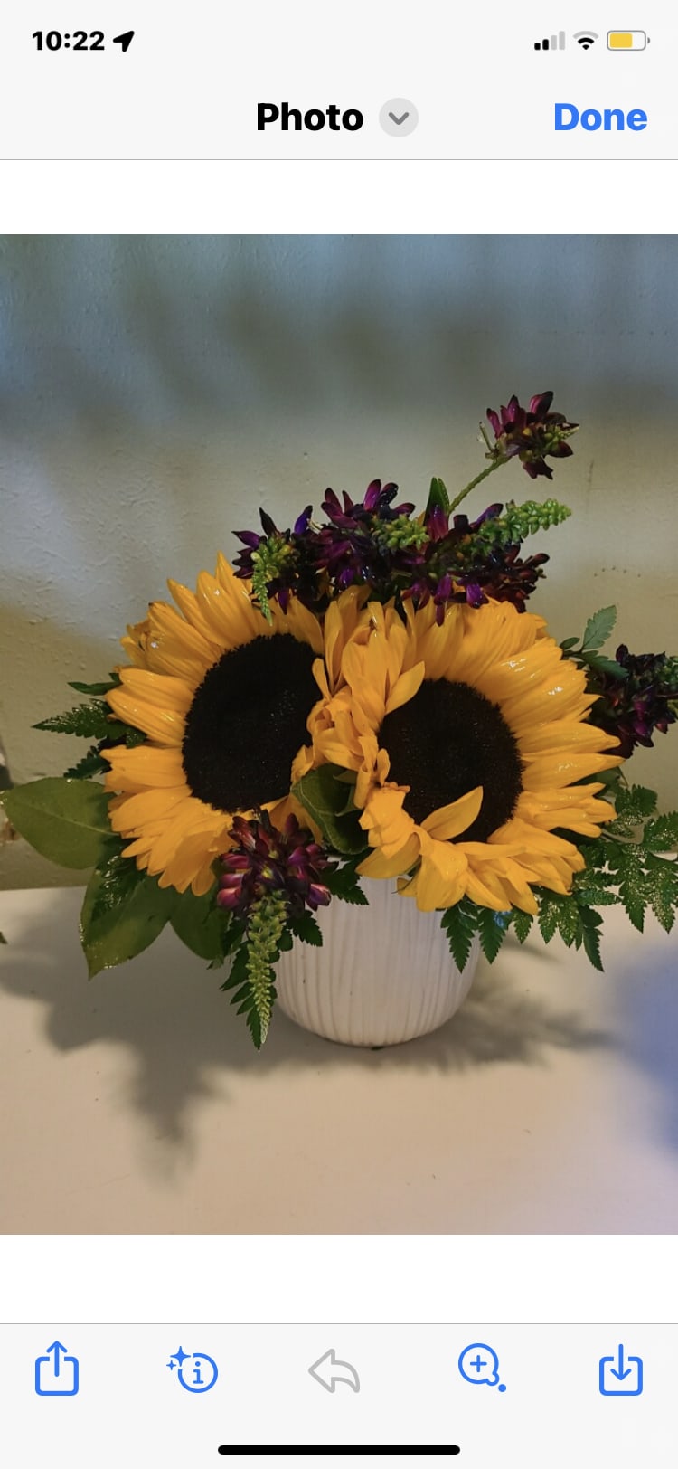 Sunflowers and purple flowers arranged in a white vase