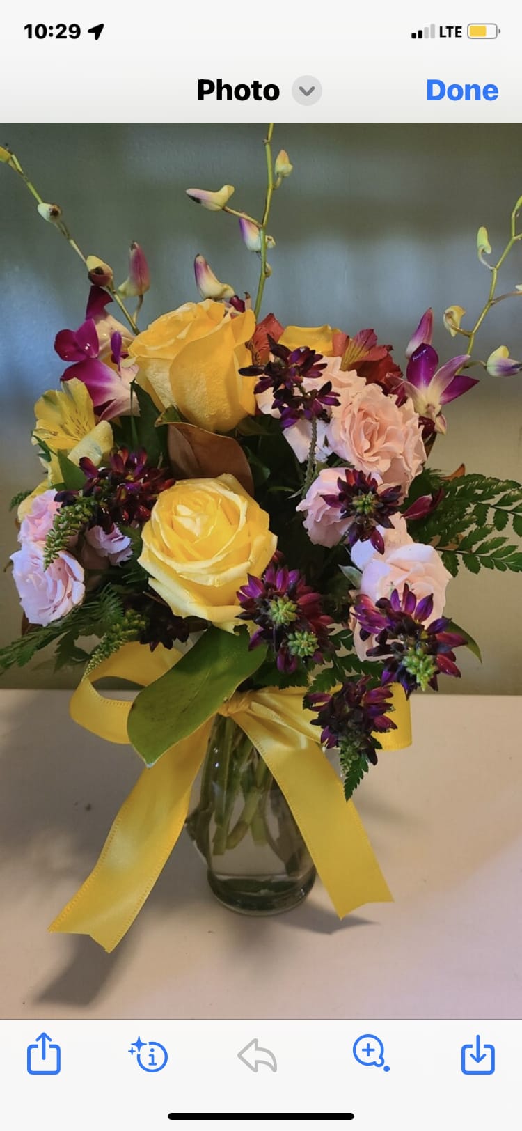 Bouquet of yellow and pink roses in a glass vase with a yellow ribbon