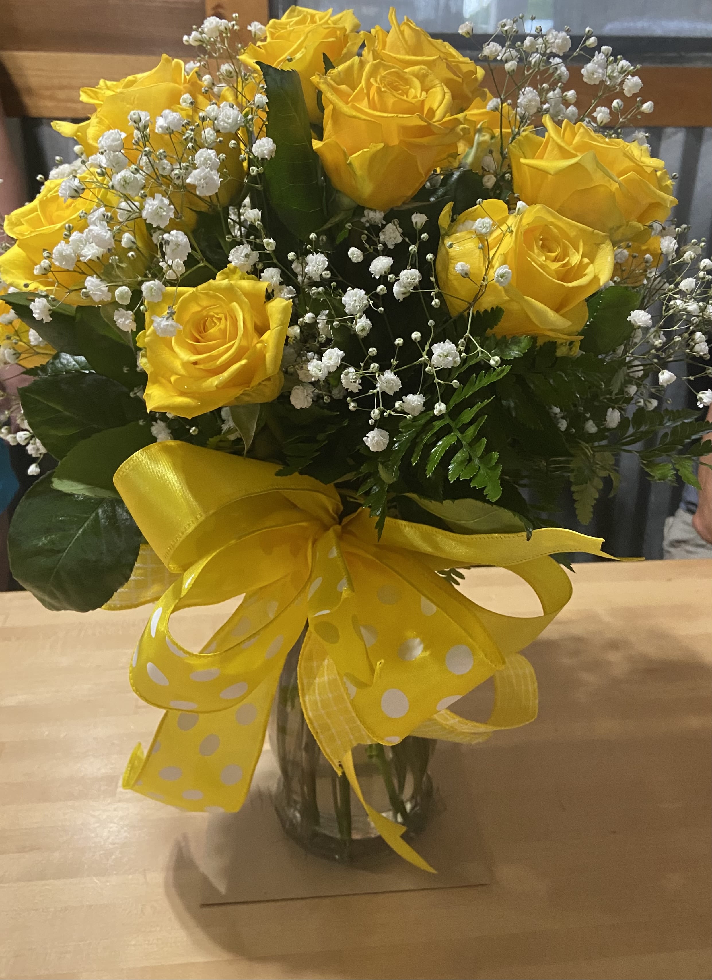 Yellow rose bouquet with baby's breath in a glass vase and yellow ribbon