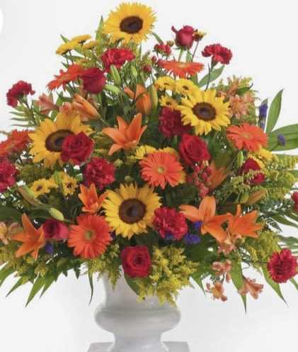 Colorful mixed bouquet with sunflowers, roses, gerbera daisies, and lilies in a white vase