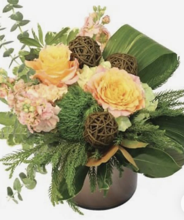 Yellow roses and pink flowers arranged in a brown vase with greenery