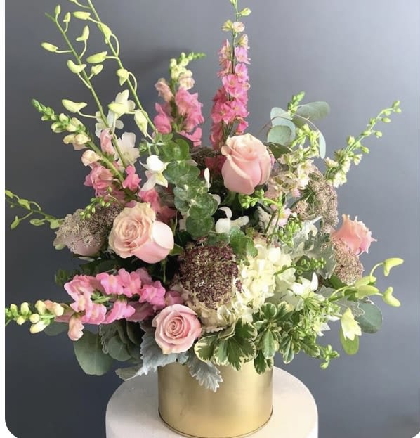 Pink and white floral arrangement in a gold cylinder vase