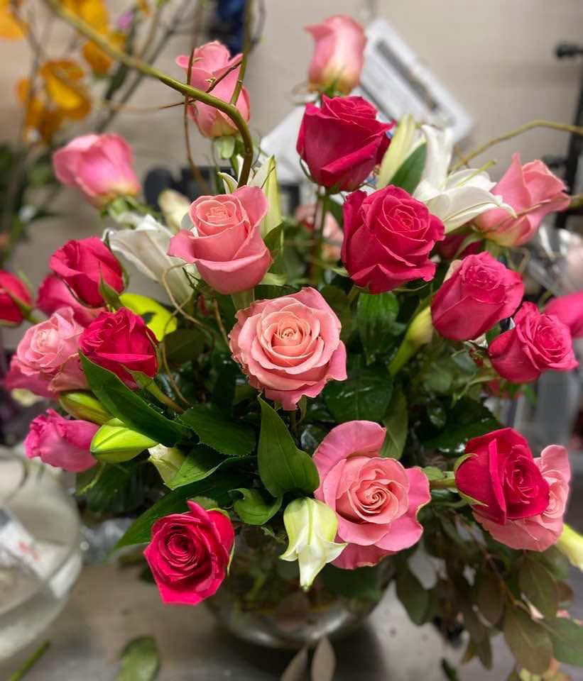 Bouquet of pink and hot pink roses with white lilies in a vase