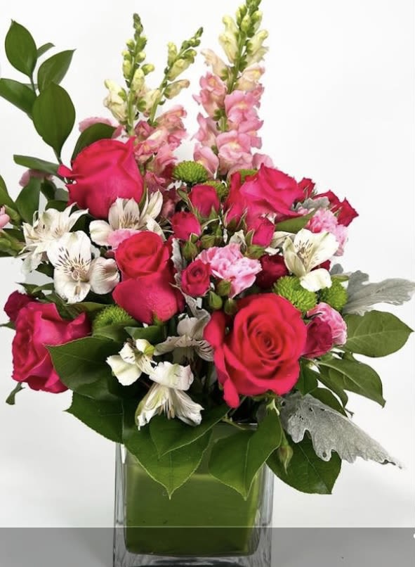 Pink roses and mixed blooms arranged in a clear glass vase
