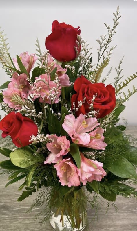 Bouquet of red roses and pink flowers in a clear glass vase