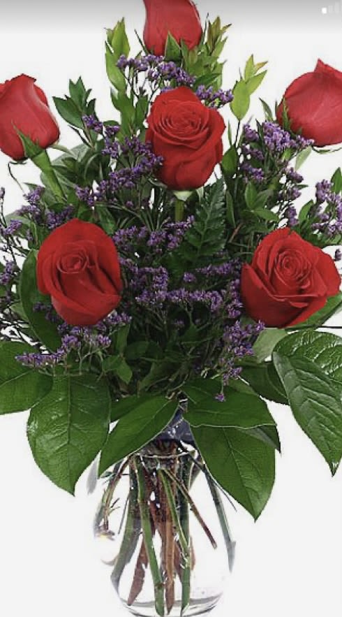 Bouquet of red roses and purple filler flowers in a clear glass vase