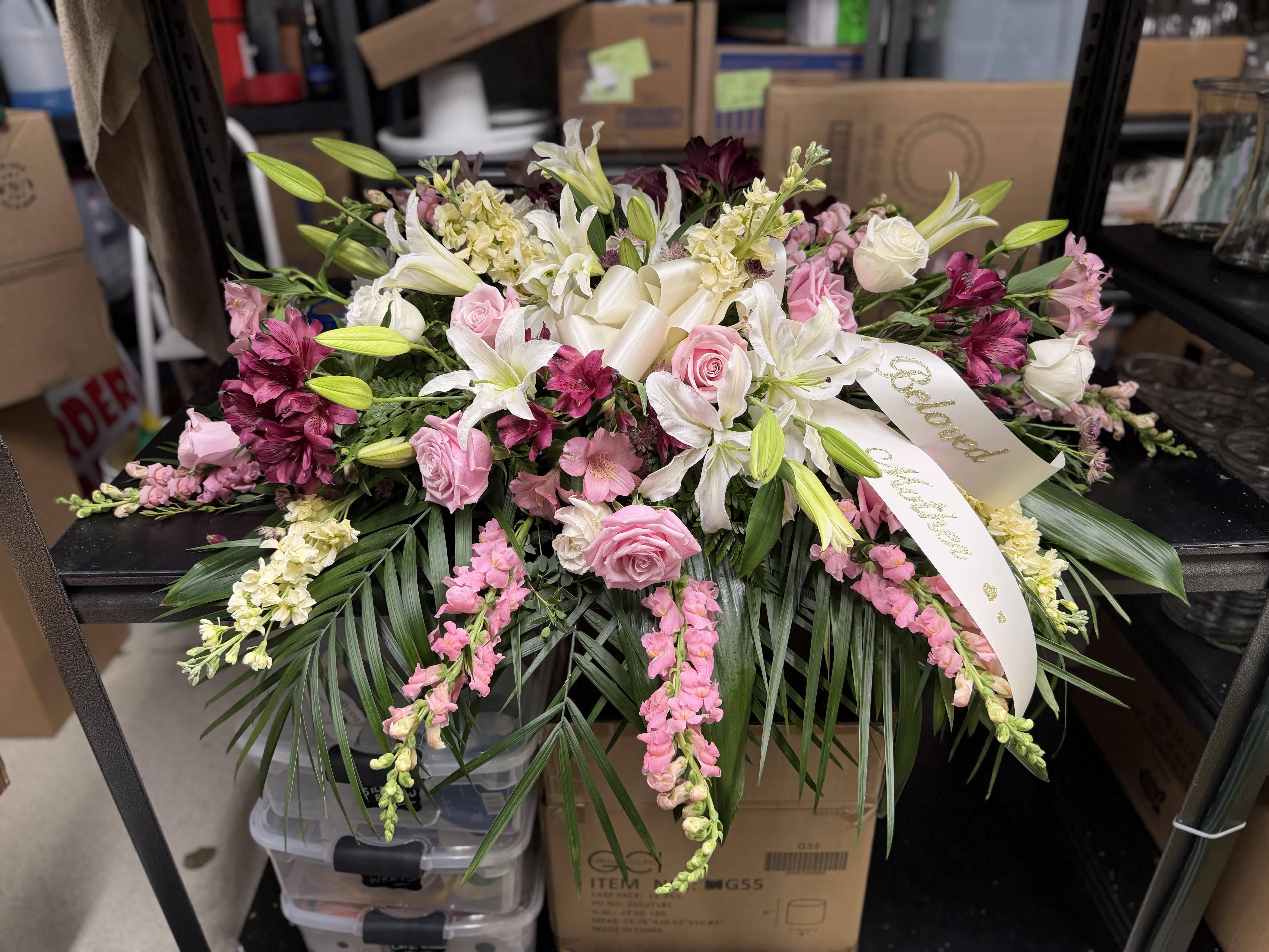 Pink and white floral spray with lilies and roses, accented by a ribbon