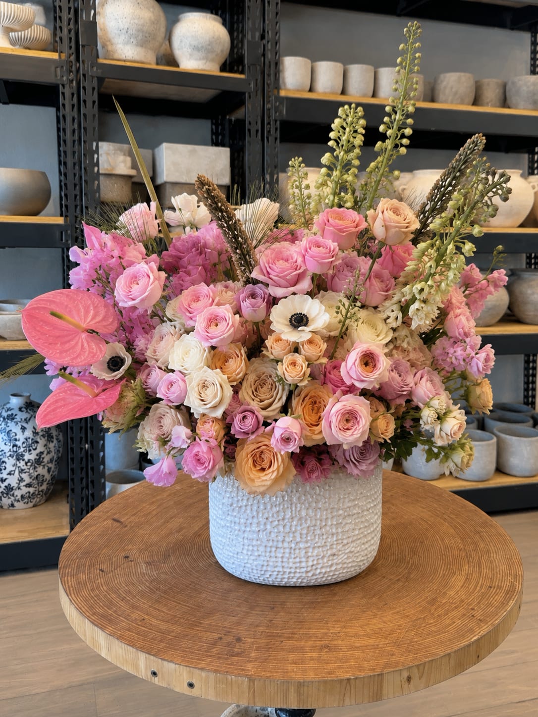 Large pastel bouquet of roses and mixed blooms in a white textured vase