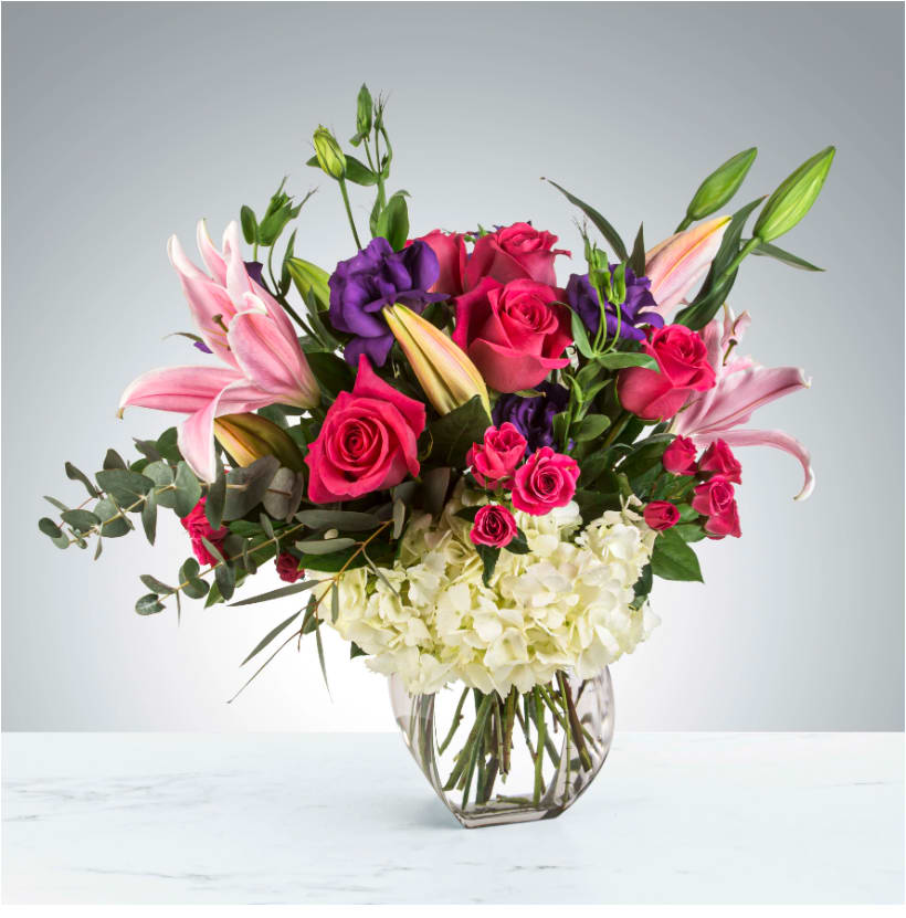 Make Plans by BloomNation™ - Bright pink roses and stargazer lilies come together with purple lisianthus and greenery for this large arrangement. Styled in a natural shape, this arrangement would impress anybody.    APPROXIMATE DIMENSIONS 22" W X 24" H