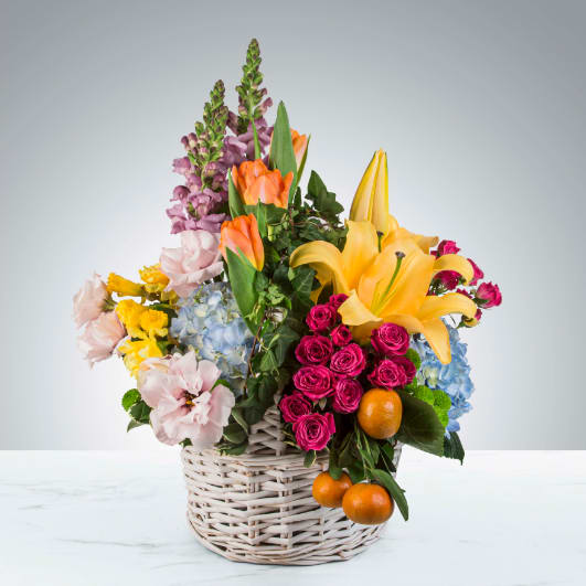 April Showers by BloomNation™ - Featuring lilies, tulips, clementines, spray roses, lisianthus, daffodils, ivy and more in a classic white wicker basket, April Showers by BloomNation™ is the ultimate spring arrangement. Short of a pollen allergy and a bunny, this is as close to gifting a season you can get. Perfect as an Easter or Passover gift, this arrangement will be sure to impress.   APPROXIMATE DIMENSIONS 17" W X 24" H