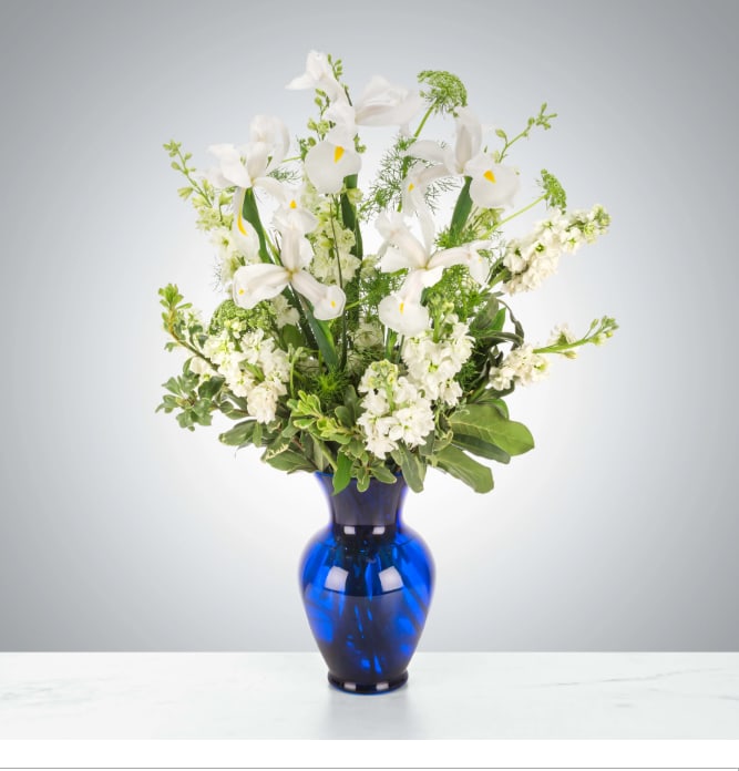 Crystal Symphony by BloomNation™ - This arrangement includes white iris, white stock, white snapdragons, and queen anne's lace in a blue vase. Send your condolences with Crystal Symphony by BloomNation™™.  Approximate Dimensions: 22"D x 30"H