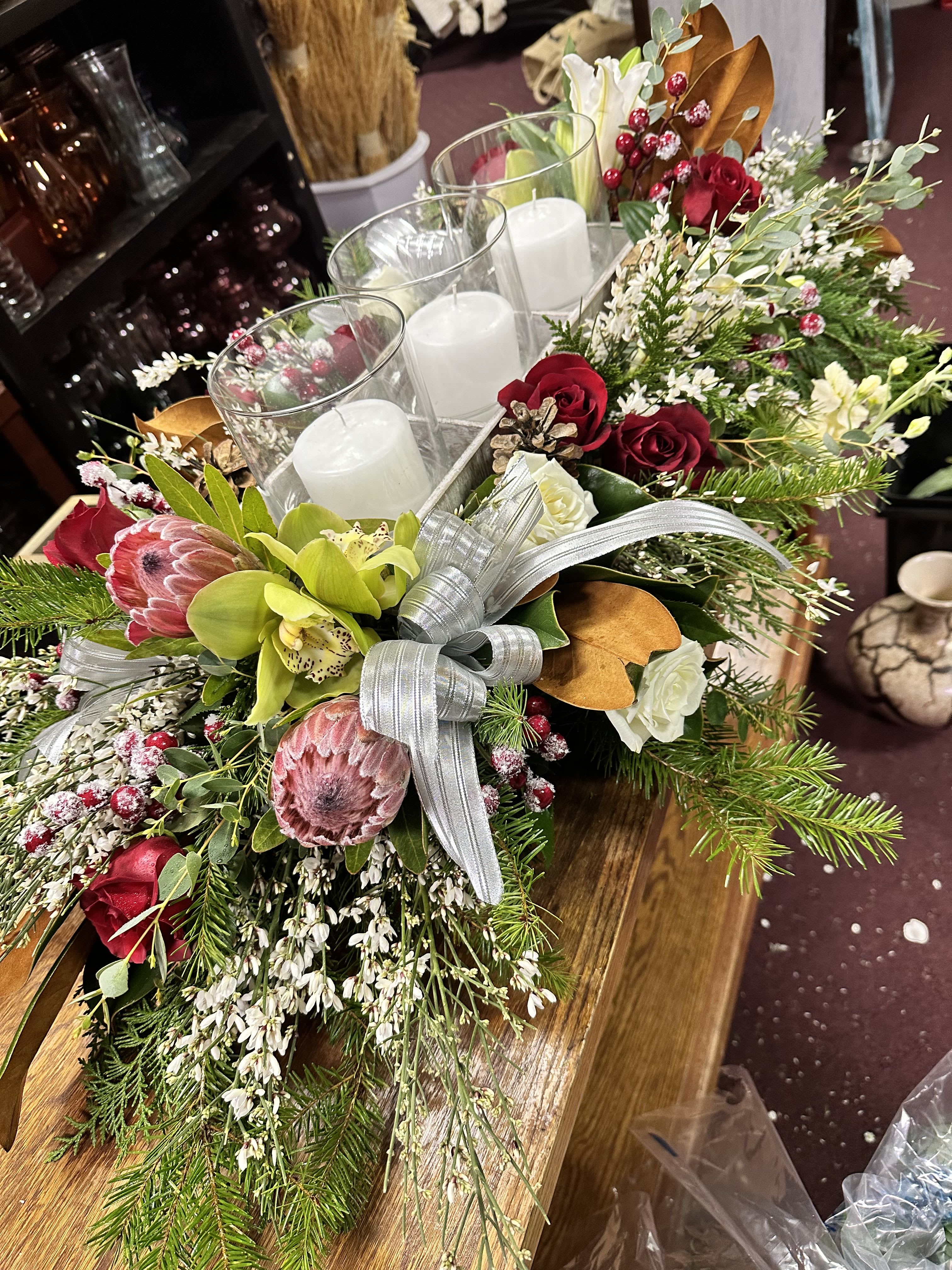 Holiday centerpiece with candles, red roses, and pink protea