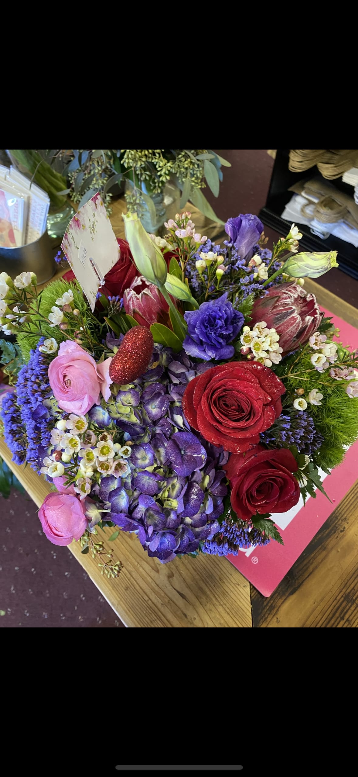 Mixed bouquet with red and pink roses, purple blooms, and green buds