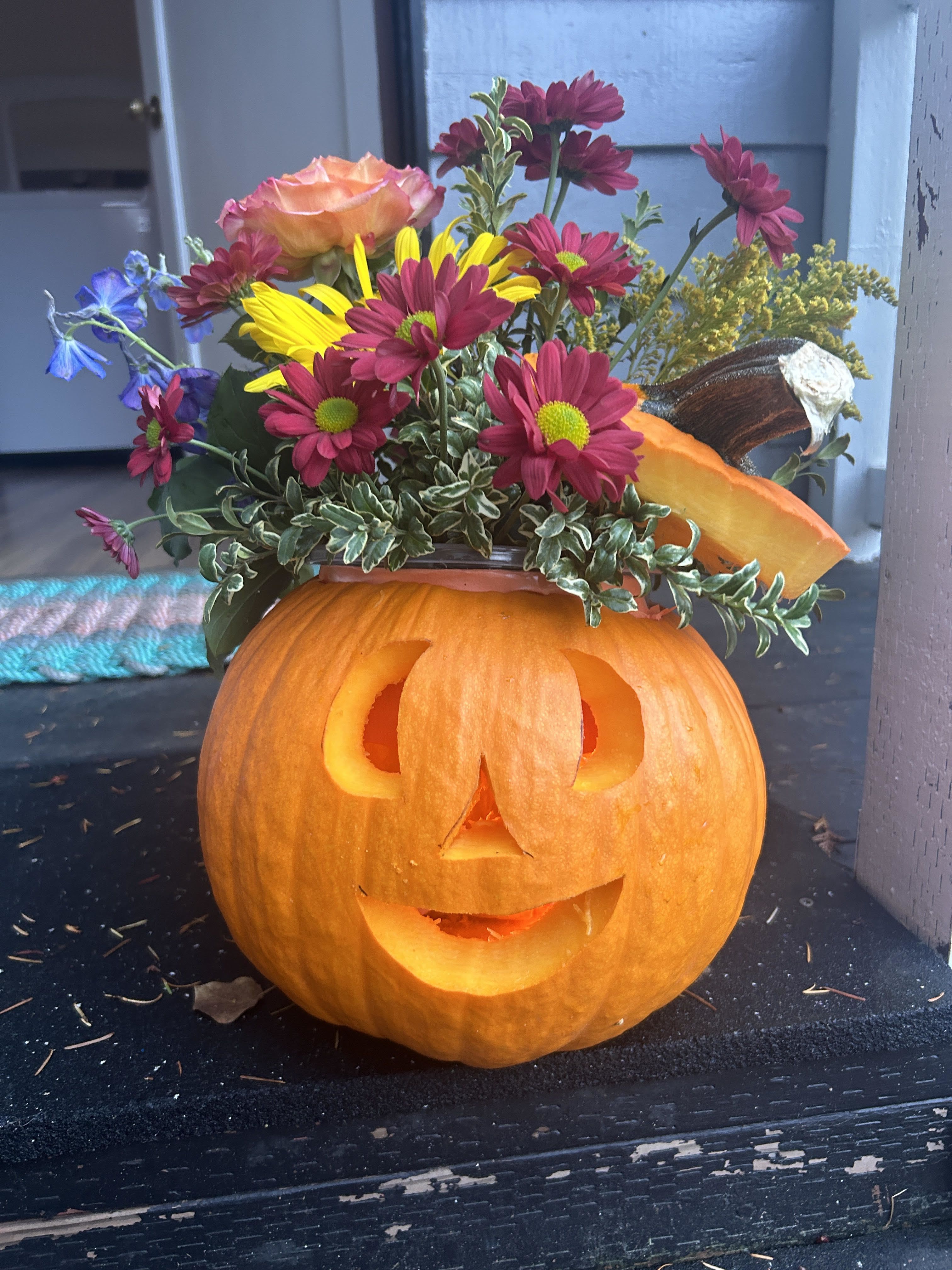 Jack-o'-lantern pumpkin with a colorful flower arrangement on top