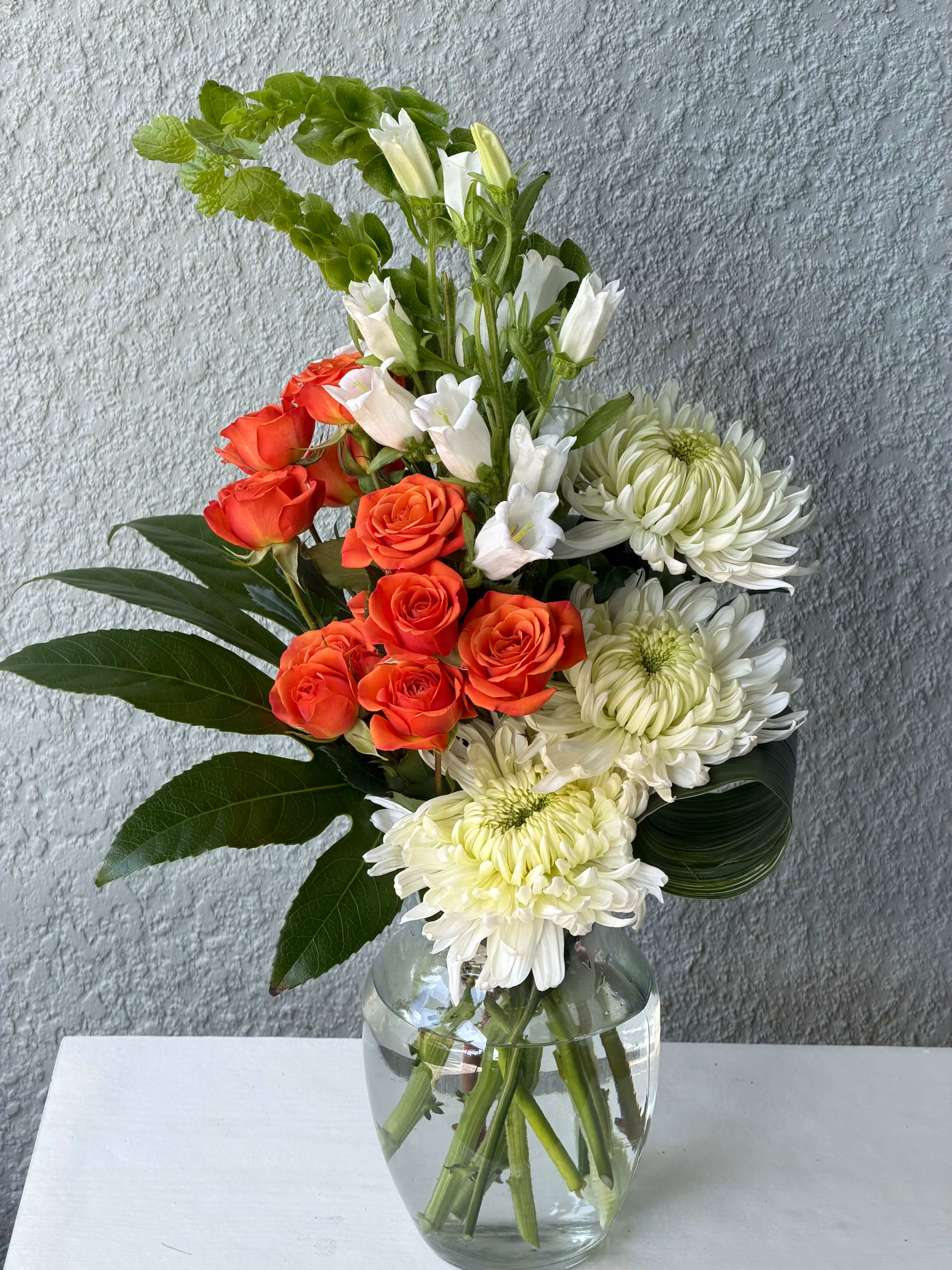 Orange roses and white chrysanthemums in a glass vase