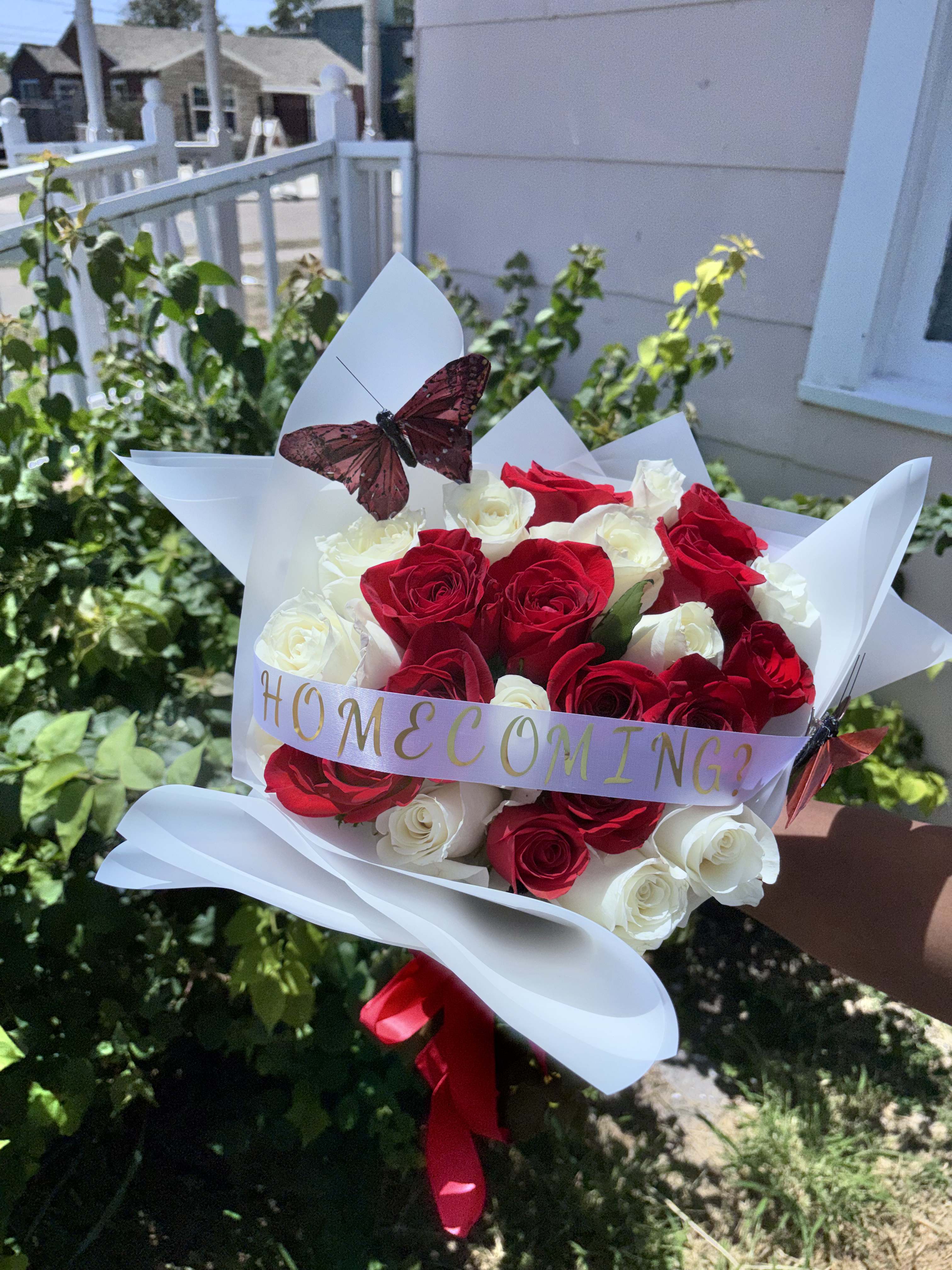 Bouquet of red and white roses wrapped in white paper with a butterfly decoration