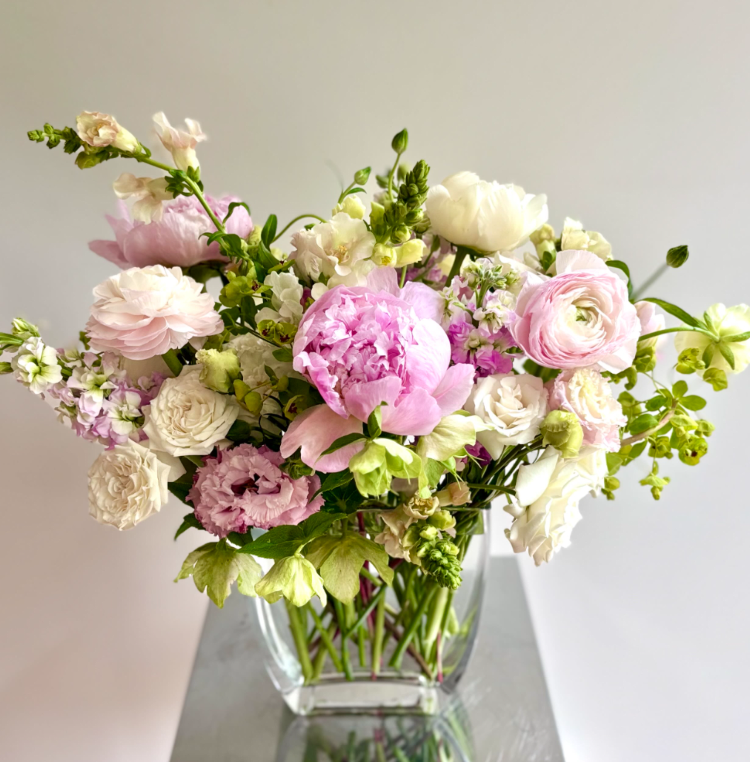 Isn't She Lovely - A lovely spring flower arrangement in soft blush pinks and whites. The mix of premium flowers usually includes line flowers such as larkspur and snapdragons, roses, ranunculus, lisianthus, stock and peonies when available.