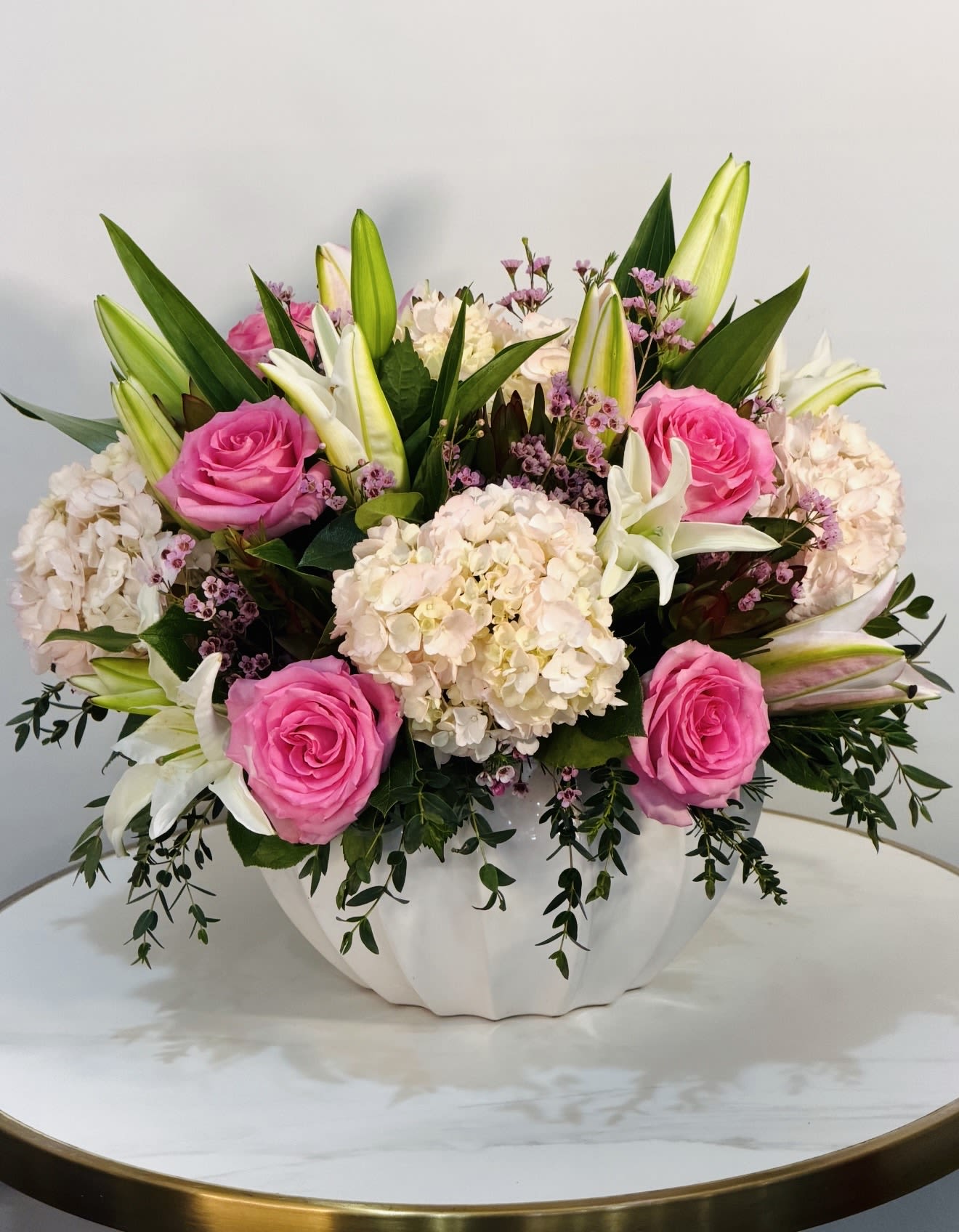 Blush Elegance - A soft and elegant floral arrangement featuring delicate pink roses, lush white hydrangea, and graceful lilies, complemented by fresh greenery and subtle seasonal accents. Designed in a modern ceramic vase, this arrangement creates a perfect balance between classic beauty and contemporary style. The combination of textures and soft color tones brings a romantic, clean, and sophisticated feel ideal for special occasions, thoughtful gifts, or adding a touch of elegance to any space. Each arrangement is handcrafted using premium fresh flowers to ensure long lasting beauty and a refined presentation. Same Day Flower Delivery Available across Beverly Hills, Bel-Air, West Hollywood, Beverly Grove, Santa Monica, Culver City, Hollywood Hills, Hollywood, Studio City, Encino, and Sherman Oaks.