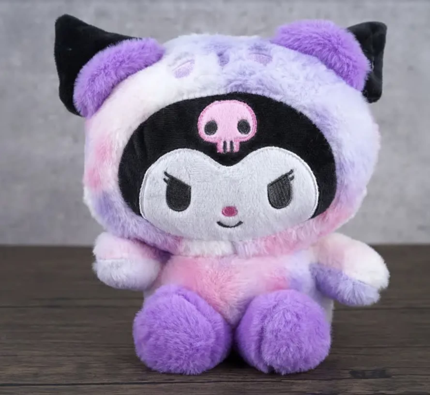 Plush character toy in a purple, pink, and black hooded outfit
