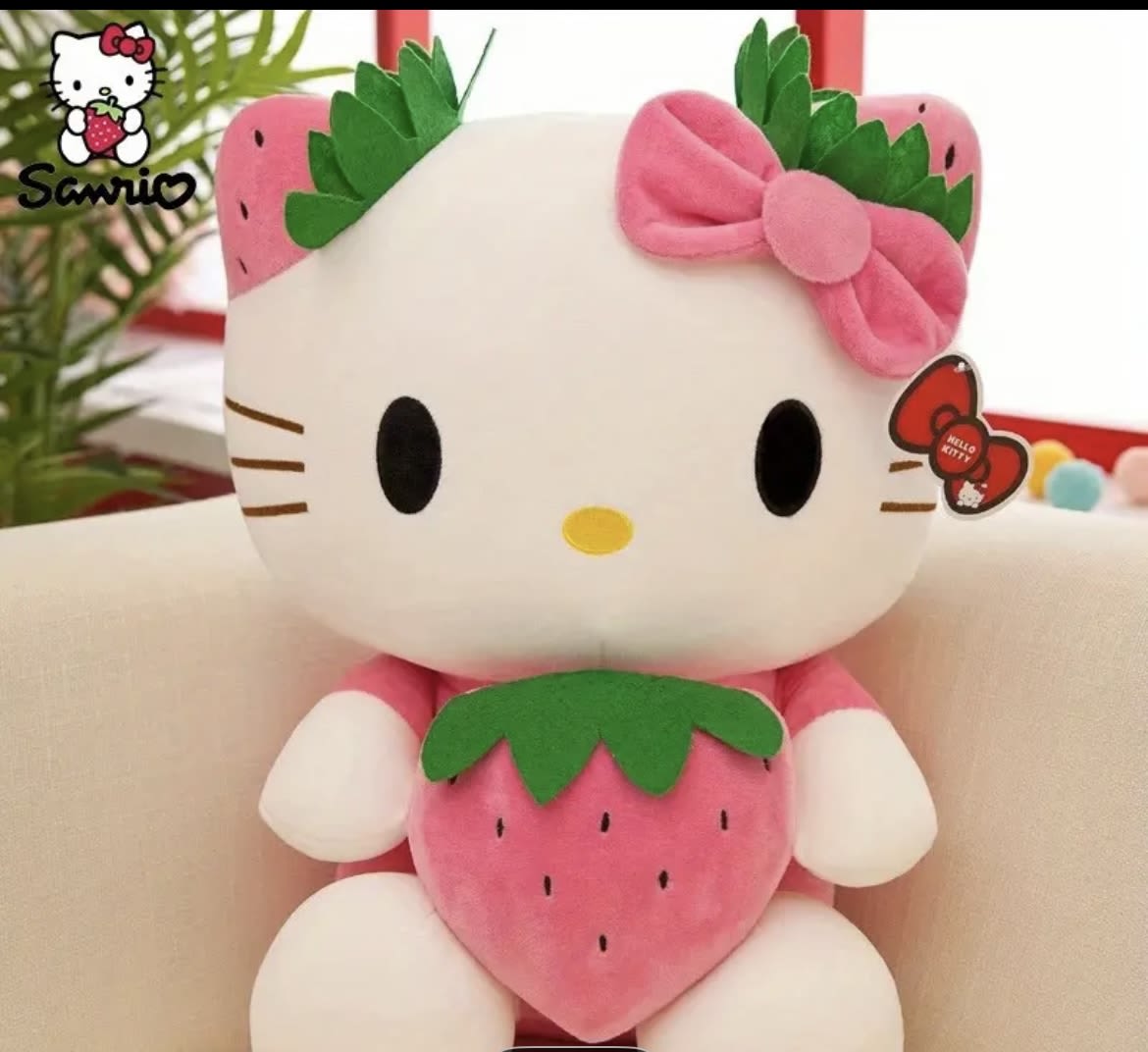 Hello Kitty plush toy holding a strawberry, with a pink bow
