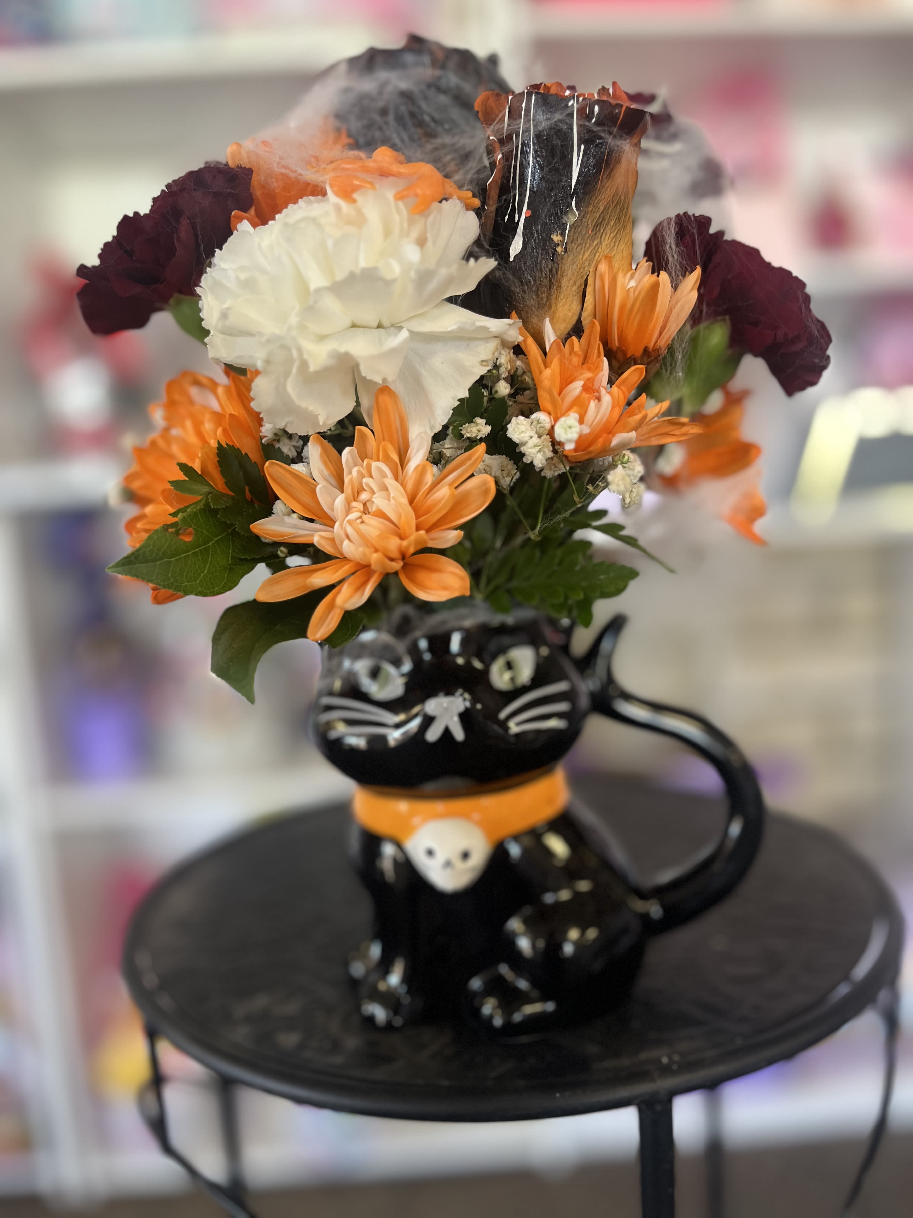 Orange and white flowers arranged in a black cat-shaped vase
