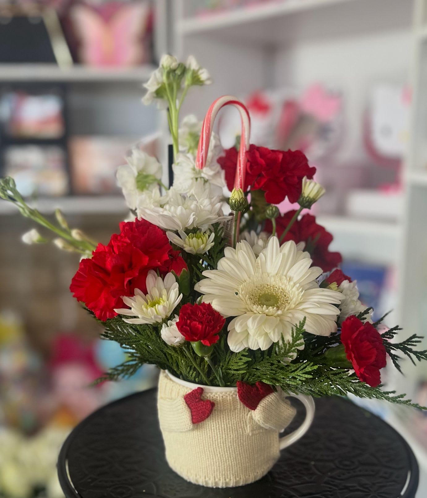 Red and white flowers arranged in a mug with a candy cane handle